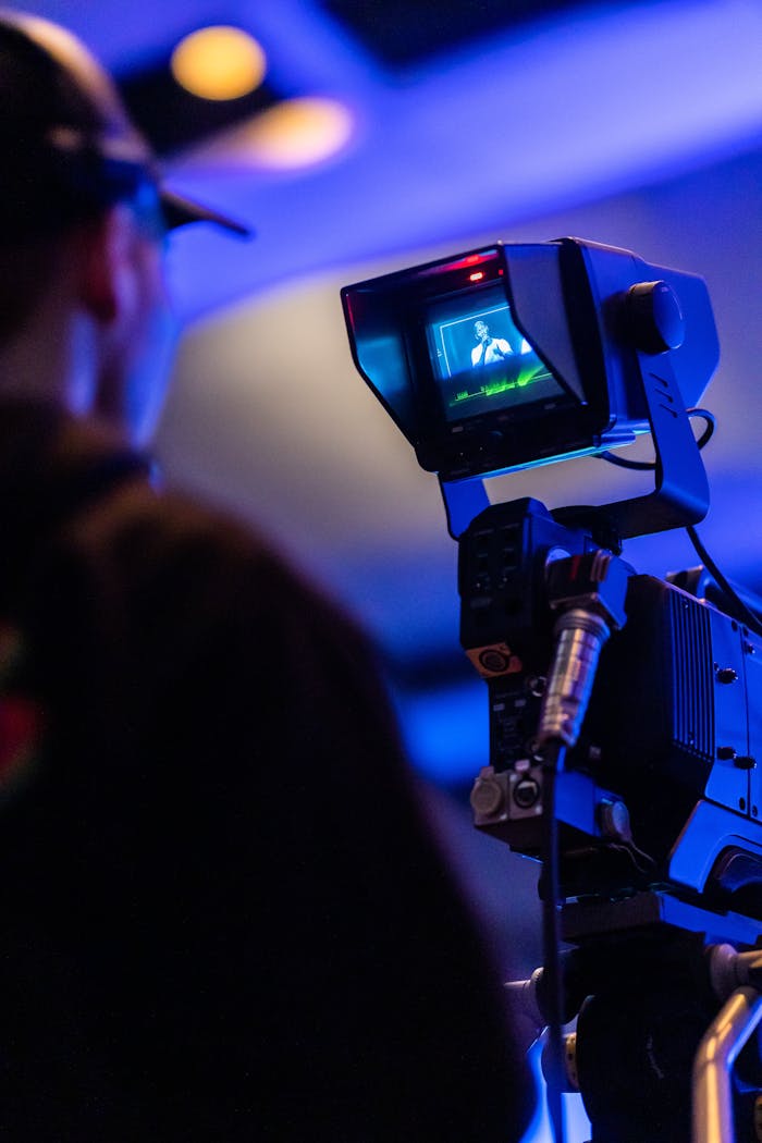 A professional filmmaker operating a high-end camera rig during a video shoot in a dimly lit environment.